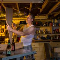 Man works in basement workshop oblivious to angry wife wearing red nightgown